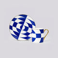 A blue and white geometric checkered cup and saucer set with gold trim, displayed on a neutral light gray background.
