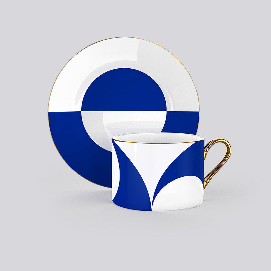 Blue and white geometric patterned teacup and saucer set with gold trim, shown on a light gray background.